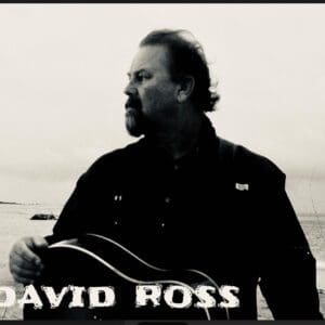 Black and white portrait of a man playing guitar.